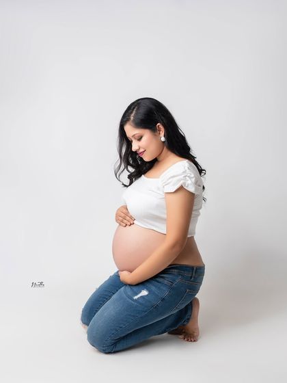 A kneeling portrait of a mom-to-be, beautifully showcasing her baby bump in a casual and comfortable style.
