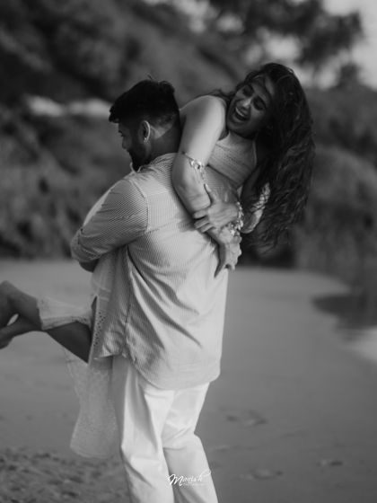 A playful and joyous moment in black and white, as the groom lifts the bride up on the beach in Goa.