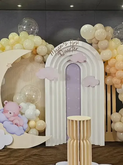 The main backdrop for a half-birthday celebration, featuring a crescent moon, a sleeping bear, and a rainbow arch, all in a soft pastel color palette.