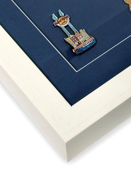 A close-up of a single guitar pin. The shadow box provides enough space so the glass doesn't press against the object, protecting its three-dimensional shape and enamel finish.