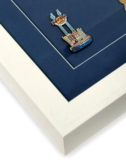 A close-up of a single guitar pin. The shadow box provides enough space so the glass doesn't press against the object, protecting its three-dimensional shape and enamel finish.