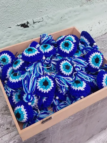 A box full of handmade evil eye keychains, ready to be shipped out.