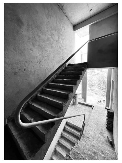 A concrete staircase under construction, where the handrail is designed as a continuous, flowing element. These photos from a site visit capture the raw, sculptural quality of the structure before the final finishes are applied.