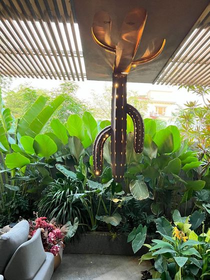 An inverted cactus sculpture made of Corten steel, which also functions as a unique light fixture. This playful and quirky piece adds a touch of humor and charm to the tropical garden setting.