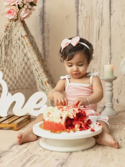 The moment the fun begins. A baby girl gets her hands into her first birthday cake during a rustic-themed cakesmash session.
