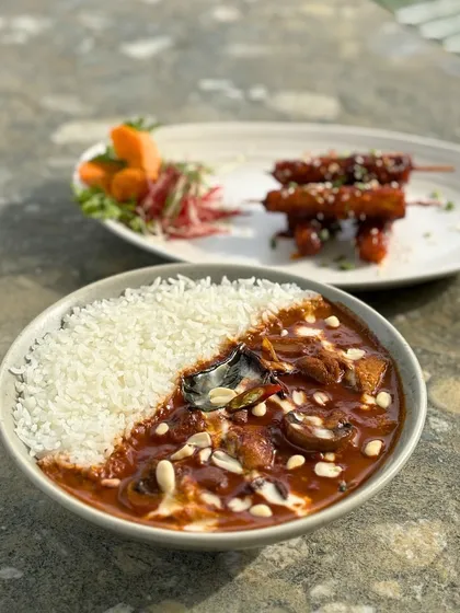 A close-up of our delicious Massaman curry, served with fluffy rice and a side of skewers. It's a hearty and flavorful meal.
