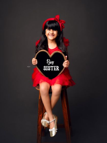 And here we have a proud Big Sister. She is absolutely adorable in her red dress, holding the announcement sign.