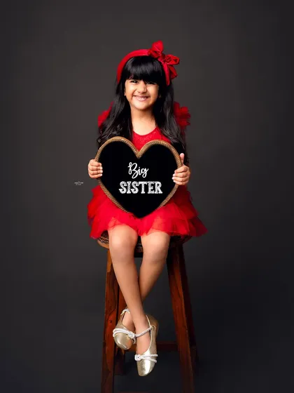 Getting ready to be a big sister! This sweet girl is all smiles as she holds a sign announcing her new role in the family.