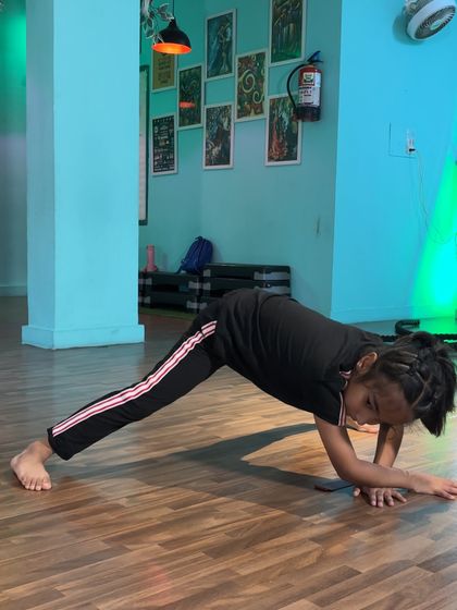 This student demonstrates a plank variation with one leg extended, an exercise that builds incredible core and shoulder stability while stretching the hamstrings.