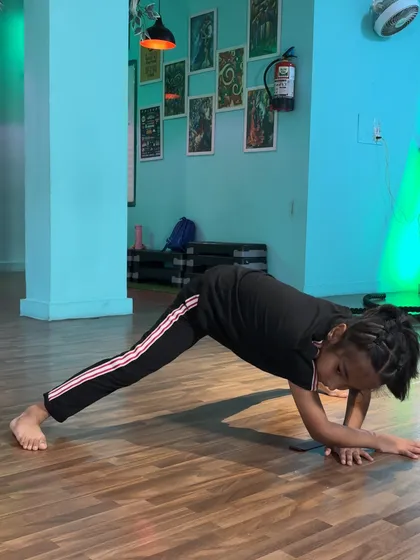 This student demonstrates a plank variation with one leg extended, an exercise that builds incredible core and shoulder stability while stretching the hamstrings.