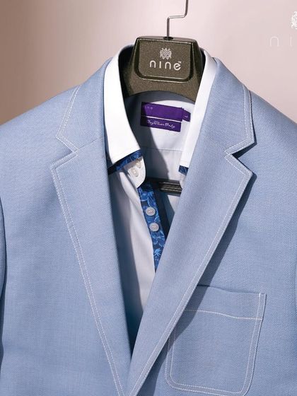 This powder blue jacket is paired with a patterned shirt, showcasing a fresh summer look. The jacket is unlined and made from a lightweight fabric for maximum comfort.
