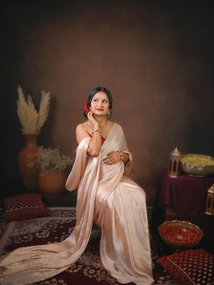 A beautiful solo portrait of the mom to be, with a red flower in her hair. The soft draping of the satin saree highlights her grace.