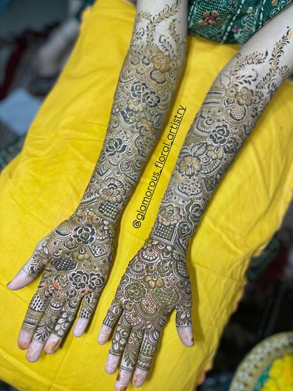 Bride Mirza's full arm mehendi, featuring a stunning combination of floral patterns and traditional motifs against a bright yellow backdrop.