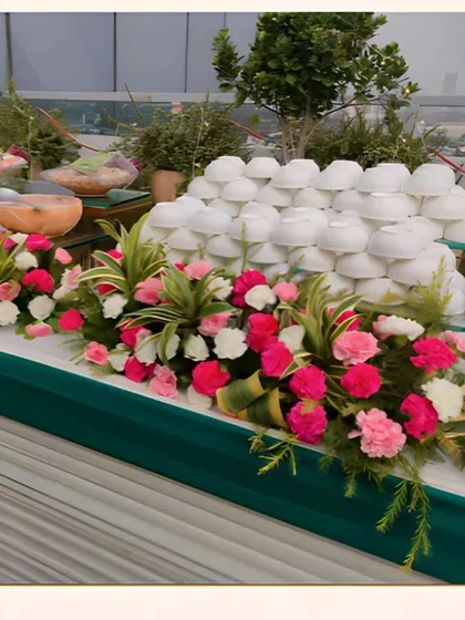 A salad and cold appetizer station set up for a rooftop party, beautifully decorated with pink and white carnations.