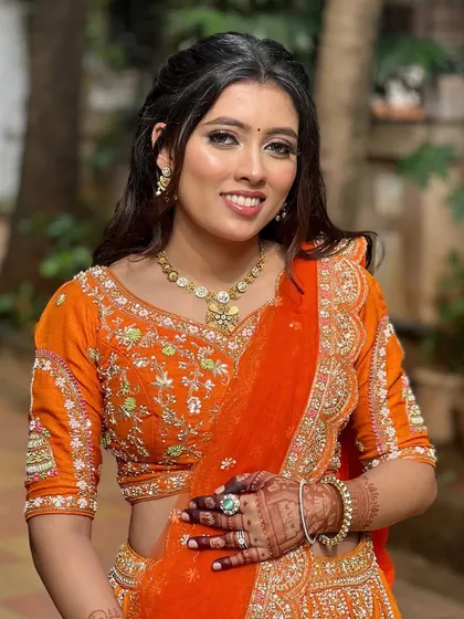 Loving this bold look with a pop of orange. The makeup is warm and vibrant, perfect for a celebration.