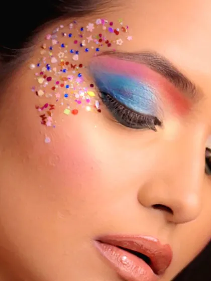 A vibrant, colorful eye makeup look with a rainbow blend of shadows and a sprinkle of chunky glitter.