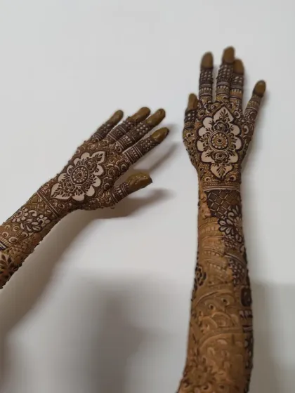 A creative pose showing both hands, with one arm fully decorated in a traditional bridal style. The mandala on the palm is a classic feature.