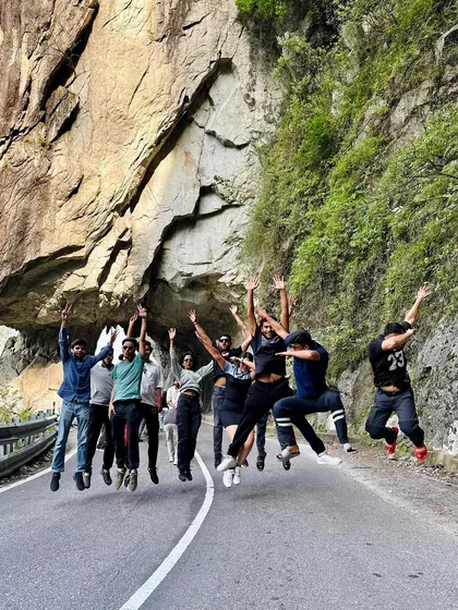 The group captured mid-air, jumping for a photo on the road. The dramatic rock formations and open road are the perfect backdrop for these fun moments.