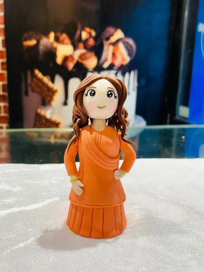 A detailed look at the handcrafted fondant figurine, showcasing the careful work on her dress and curly hair.