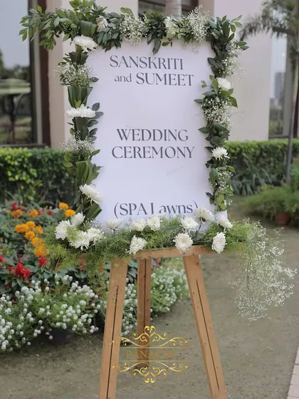 A simple and elegant welcome easel, framed with fresh white flowers and greenery, directing guests to the spa lawns.