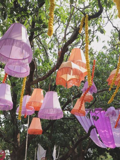 A detail shot of the colorful lampshades hanging from a tree as part of the mehendi decor.