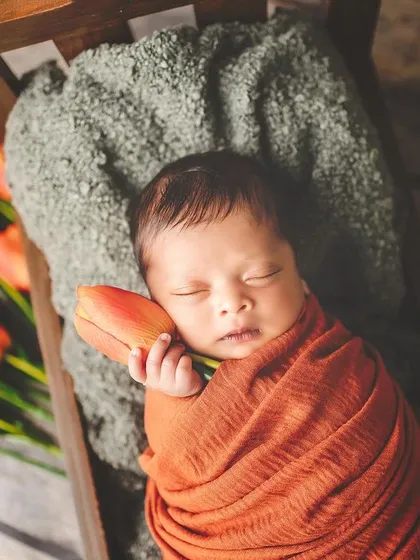 A tiny hand holds a single tulip, a symbol of new life and love. This artistic shot captures the delicate connection between your baby and the beautiful world around them.