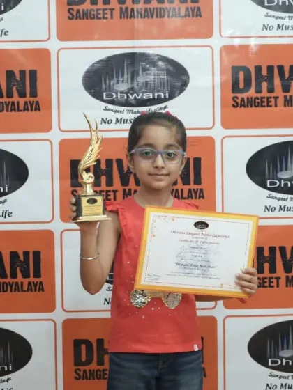 A young student proudly holds her certificate and trophy for her drawing.