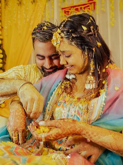 An intimate moment between the couple during their haldi, surrounded by the yellow hues of turmeric and flowers.