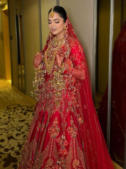 Another angle of this timeless red bridal look, showcasing the flawless base and the way the makeup complements the heavy gold jewelry and intricate outfit.