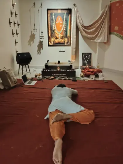 A seeker lies in a posture of surrender before the Devi Yantra during an Amavasya night. The space allows for personal and profound expressions of devotion.