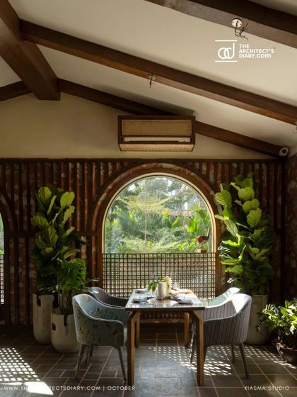 An interior dining space at Sanctuary Bar, with a large arched window looking out onto the garden. The design ensures that the connection to the lush landscape is maintained even when indoors.