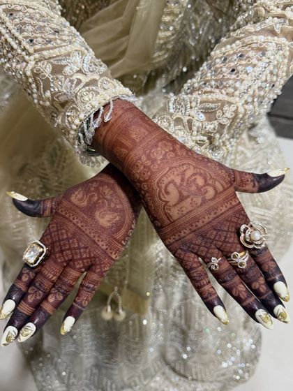 The final stain is everything. This close-up shows the deep, rich color of the bridal mehendi, adorned with beautiful rings and a stunning outfit.