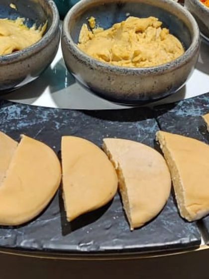 Freshly baked pita bread, sliced and ready to be paired with our selection of homemade hummus and other dips.