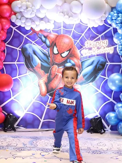 The birthday boy, dressed in his own Spider-Man suit, stands proudly in front of a backdrop I designed just for him. Seeing his happy face makes all the planning worthwhile.