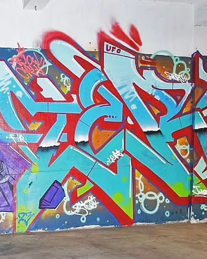 A full view of the red and blue wildstyle piece, flanked by other artists' work, showing a typical collaborative graffiti wall.