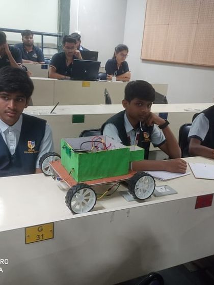 A team of students sits with their wheeled robot, reviewing their strategy during the championship at IIT Bombay.
