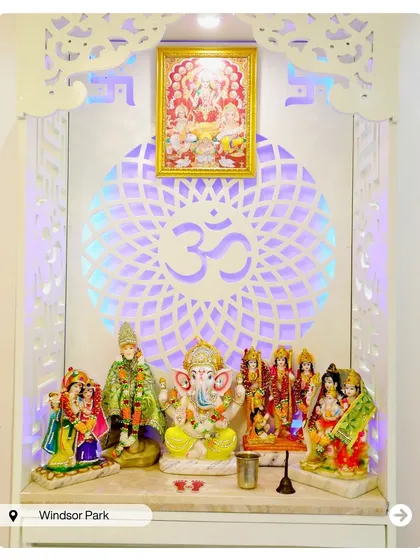 A vibrant and beautiful pooja ghar with a backlit 'Om' mandala. The space is filled with colorful idols, creating a joyful and divine atmosphere.