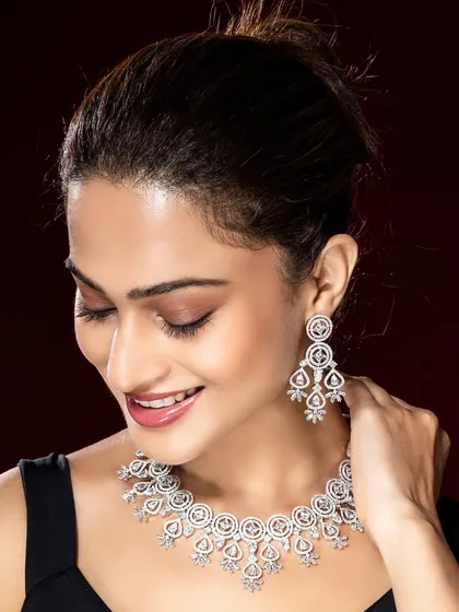 This elegant shot features a model wearing a classic diamond necklace against a deep red background. The contrast and sophisticated pose are ideal for luxury brand advertising.