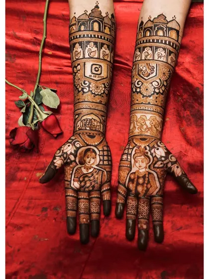 Your mehendi is a key part of your bridal look. This design shows how custom portraits and story elements, like the Instagram logo with a special date, come together against a beautiful red lehenga.