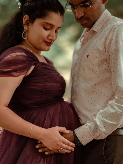 A close-up shot focusing on the hands and the bump. This image highlights the details: their interlaced fingers and the rich fabric of her dress, symbolizing their connection and the life they've created.