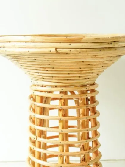 A close-up of our flared rattan pedestal table or stand. The combination of a tightly coiled top and an open-weave base creates a visually interesting piece, ideal for displaying a plant or a decorative object.