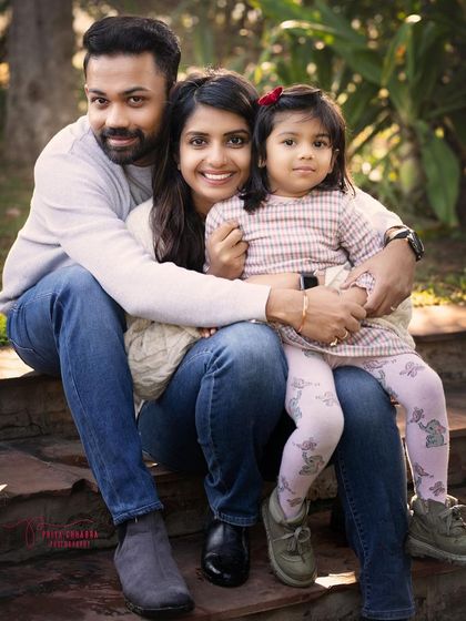 A happy family of three sitting together on outdoor steps. Outdoor sessions are perfect for relaxed, natural family portraits where everyone can feel comfortable.