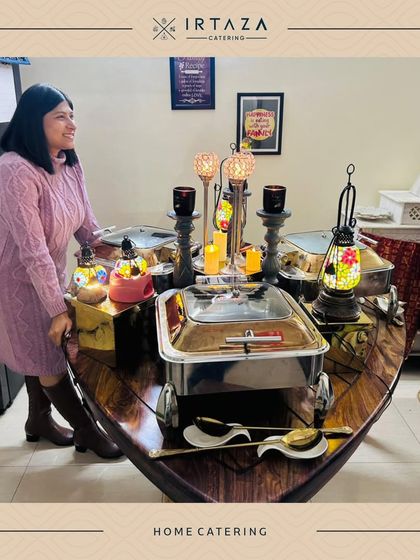 A happy client enjoying the beautiful boat-shaped table setup we created for her intimate home catering event.