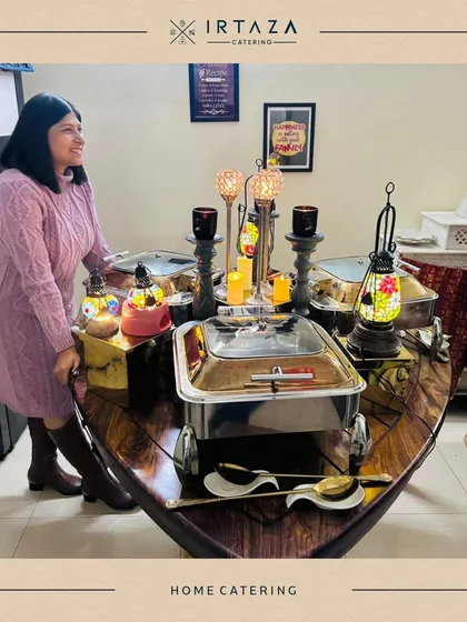 A happy client enjoying her beautifully arranged home catering setup. The boat-shaped table adds a unique and whimsical touch to this intimate dinner party.