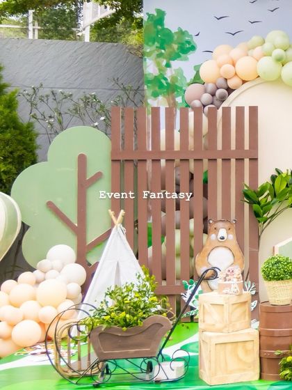 A detailed view of the woodland setup, showing a miniature teepee, a wooden cart filled with plants, and a bear cutout in the background.