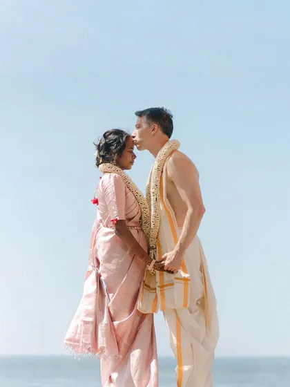 A husband's gentle kiss on his wife's forehead. This tender portrait of Bhavana and Michael, dressed in traditional South Indian wedding attire against the open sky, is a symbol of love and respect.