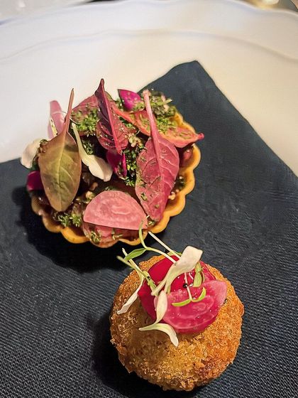A duo of amuse-bouche: a beet tartlet and a confit duck croquette. A perfect pairing of earthy and rich flavors.