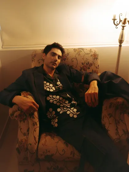A relaxed portrait of Ishwak Singh for Hindustan Times, seated in a vintage armchair under warm, ambient light.