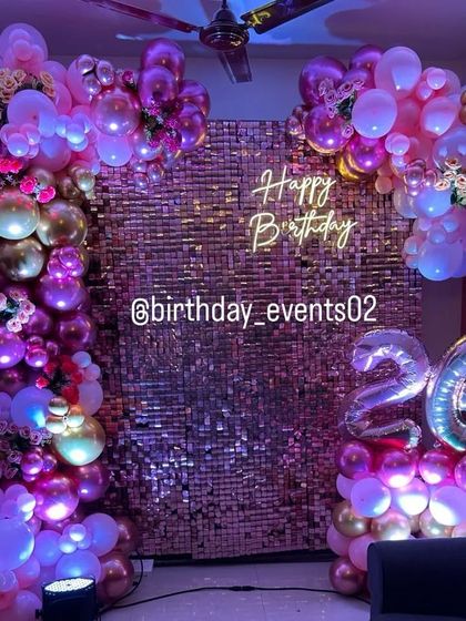 The party atmosphere is electric with this rose gold sequin wall and balloon setup, enhanced with purple mood lighting.