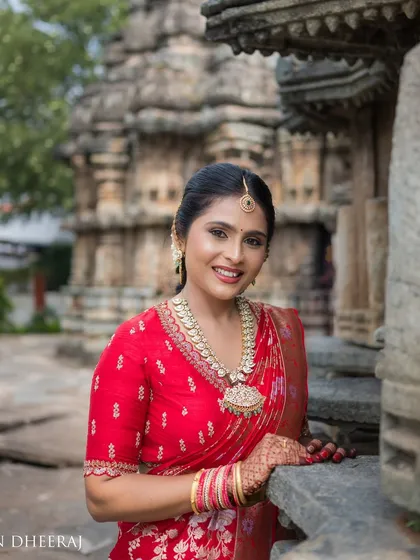 A smiling bride in her red saree and custom blouse. The outfit was designed to be both beautiful and comfortable for her outdoor pre-wedding shoot.
